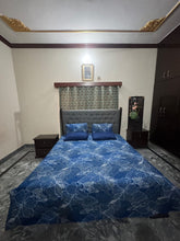 Bedroom with a bed featuring a blue floral patterned comforter, nightstands, and a dresser.